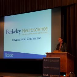 Dan Feldman speaking at a podium with a screen next to him that says “Berkeley Neuroscience, Helen Wills Neuroscience Institute, 2022 Annual Conference” with the UC Berkeley logo.